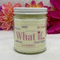 A hand poured candle with label that says What If and other positive words, with white lid and bright floral background.
