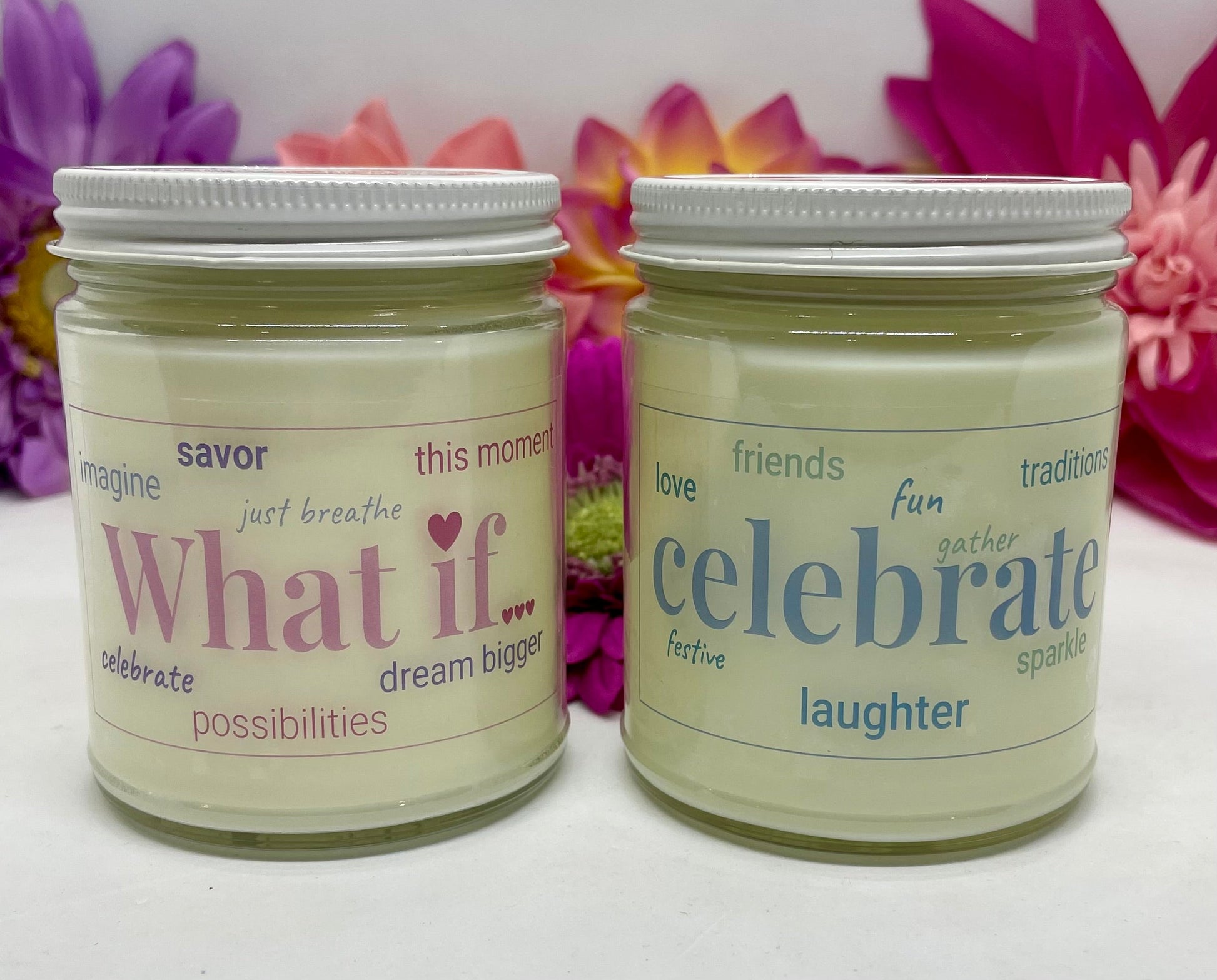 2 hand poured candles with labels that each say What If and Celebrate with white lids and bright floral background.