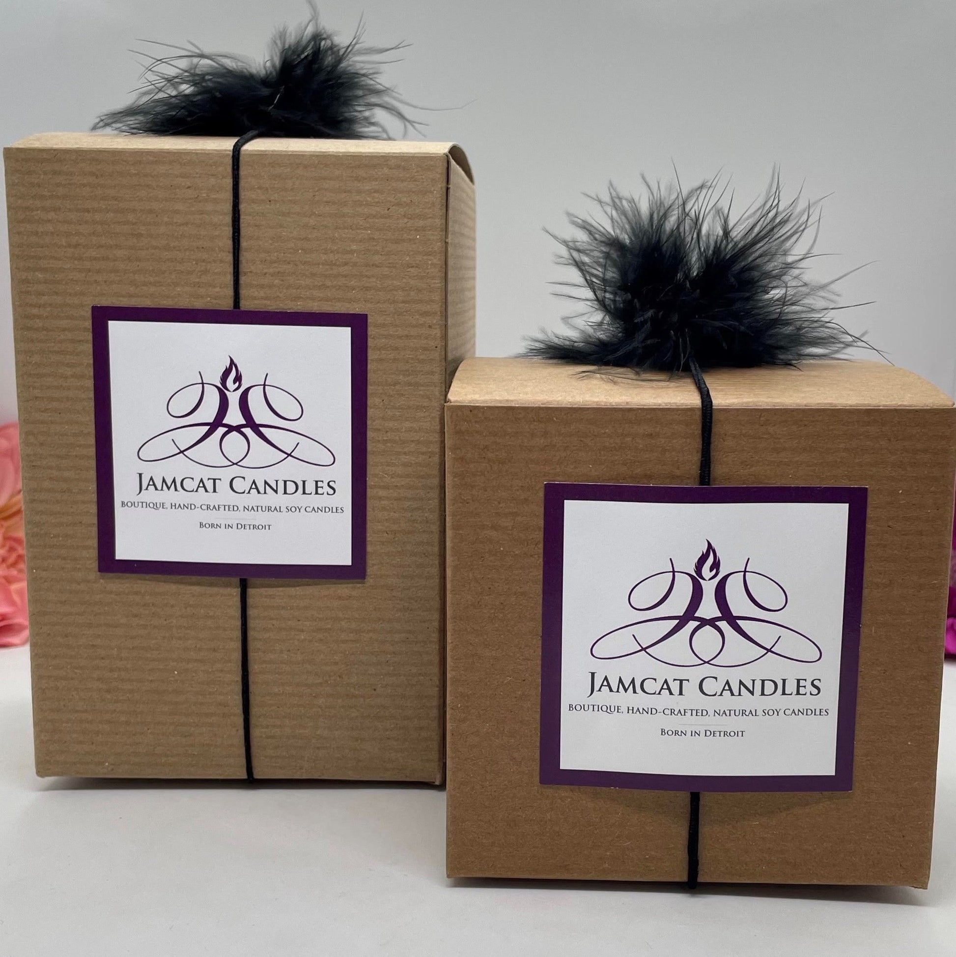 Kraft gift boxes in 2 sizes decorated with a Jamcat Candles logo card and black feather puff elastic.